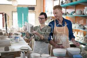 Male and female potter checking plate