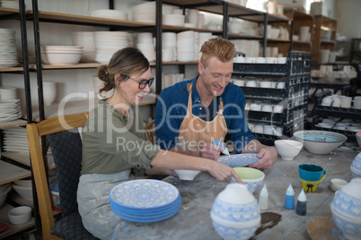 Male and female potter decorating bowl