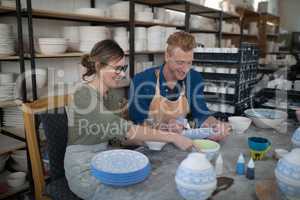 Male and female potter decorating bowl