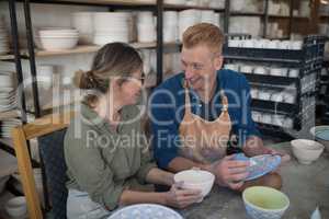Male and female potter interacting while decorating earthenware