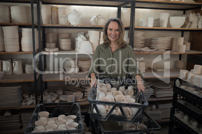 Portrait of female potter holding cups in crate
