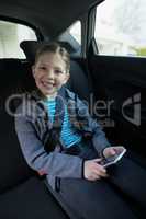 Teenage girl using mobile phone in the back seat of car