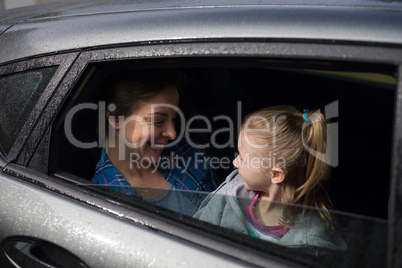 Mother and daughter interacting in the back of the car