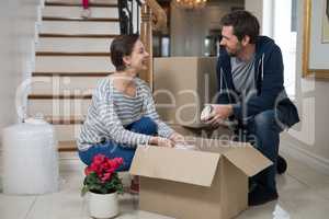 Couple opening cardboard boxes in living room