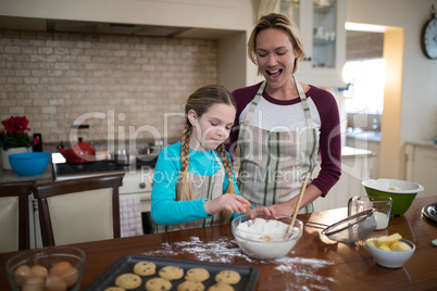 Mother and daughter preparing cookies in kitchen