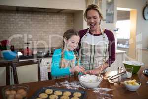 Mother and daughter preparing cookies in kitchen