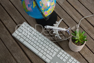 Pot plant, globe, keyboard and airplane model on wooden plank