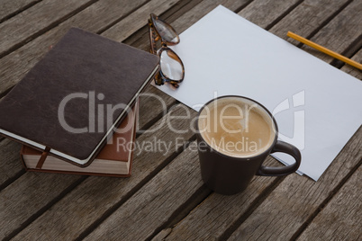Organizer, coffee, spectacles, pencil and paper on wooden plank