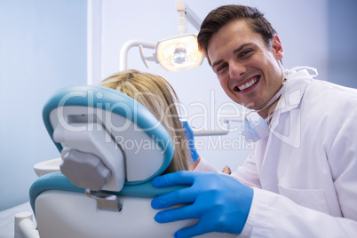 Portrait of happy dentist examining woman