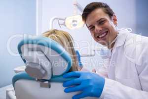 Portrait of happy dentist examining woman