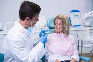 Side view of young doctor showing dental mold to patient
