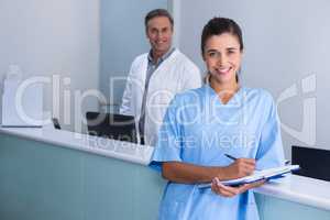 Smiling doctors standing against wall at clinic