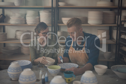 Male and female potter decorating bowl