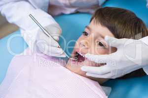Cropped image of dentist holding equipment while examining boy