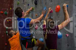 Athletes with trainer climbing wall in gym