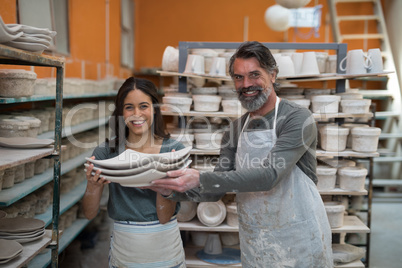 Portrait of male and female potter holding ceramic plates