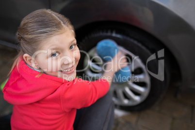 Teenage girl washing a car on a sunny day