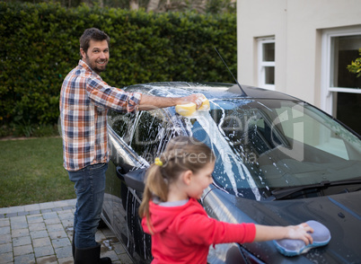 Teenage girl and father washing a car