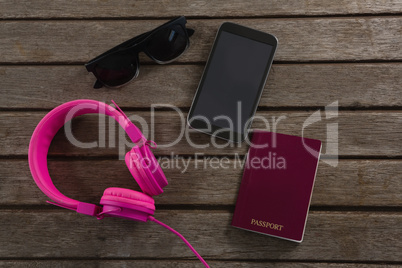 Headphones, sunglasses, passport and mobile phone wooden plank