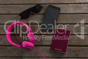 Headphones, sunglasses, passport and mobile phone wooden plank