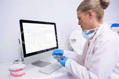 Side view of dentist working while sitting by computer