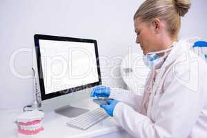 Side view of dentist working while sitting by computer