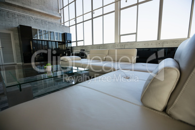 Glass table by empty white sofa at office