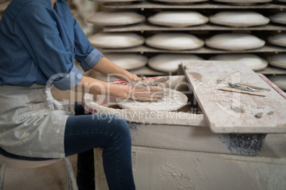 Mid section of female potter molding a clay