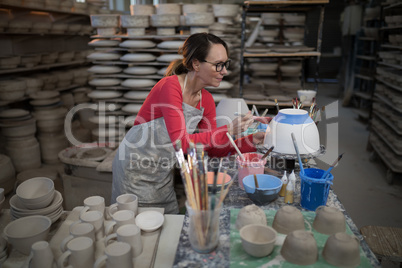 Female potter painting bowl