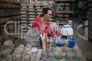 Female potter painting bowl