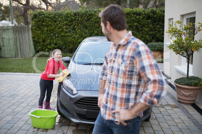 Teenage girl and father washing a car