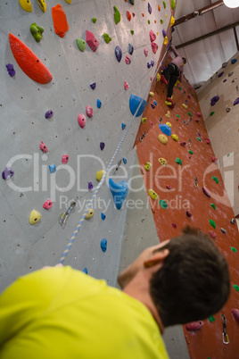 Man looking at female athlete climbing wall in club