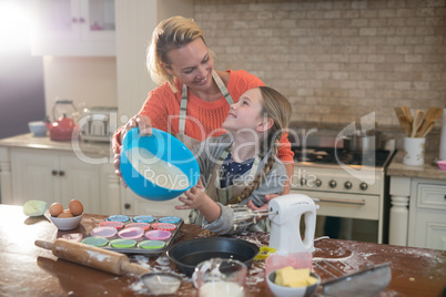 Mother and daughter preparing cup cake in kitchen