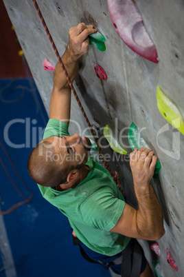 High angle view of confident athlete climbing wall in health club