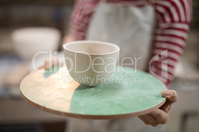 Mid section of female potter holding bowl