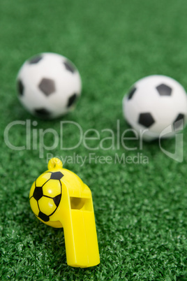 Whistle and footballs on artificial grass