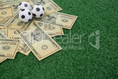 Footballs and currency notes on artificial grass