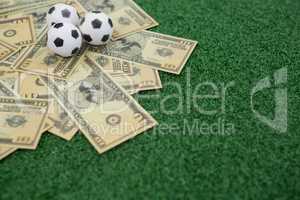 Footballs and currency notes on artificial grass