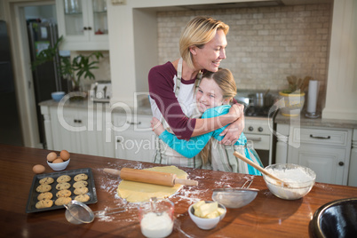 Mother and daughter embracing each other while preparing cookies