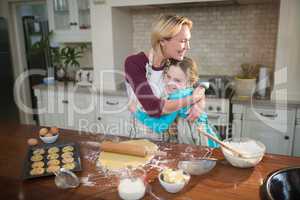 Mother and daughter embracing each other while preparing cookies