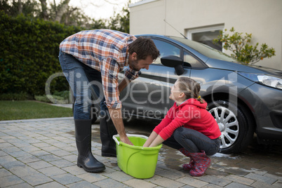 Teenage girl and father washing a car