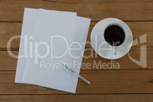 Black coffee and blank paper on wooden plank