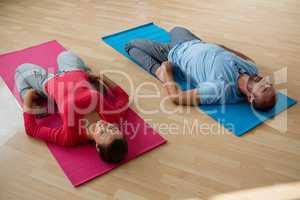 Instructor with student practicing reclined hero pose in yoga studio