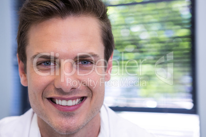 Dentist standing against window at clinic