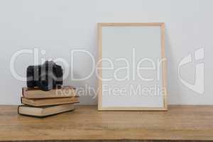 Picture frame, books and digital camera on table