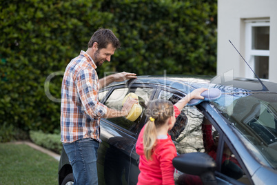 Teenage girl and father washing a car