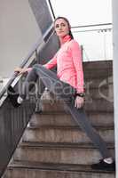 Woman performing stretching exercise in the stairs