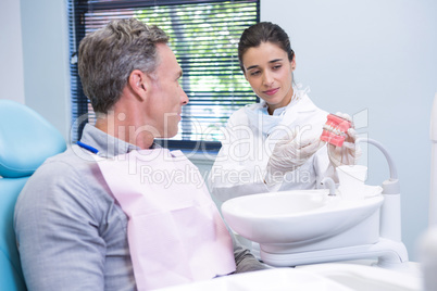 Happy dentist showing dental mold to man