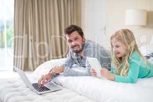 Father and daughter using laptop and digital tablet