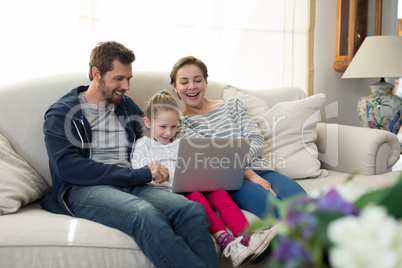 Parents and daughter using laptop